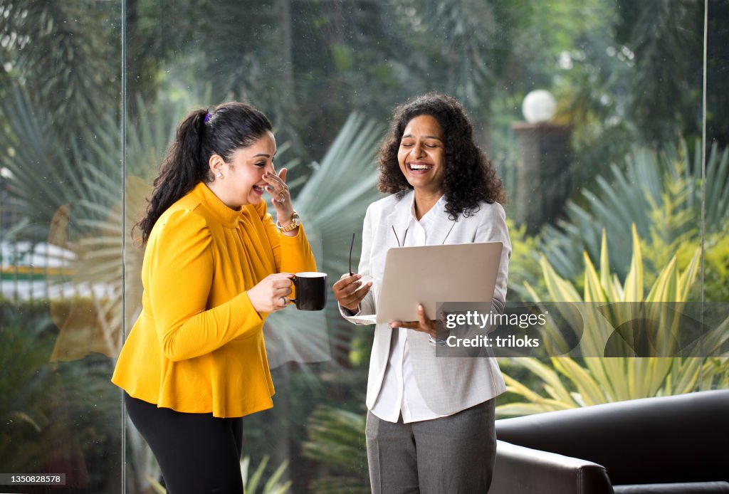 Two happy businesswomen discussing at office
