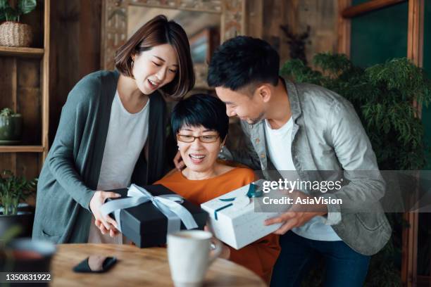 a senior asian mother receiving presents from her daughter and son at home. family love. the joy of giving and receiving - chinese mothers day stock pictures, royalty-free photos & images