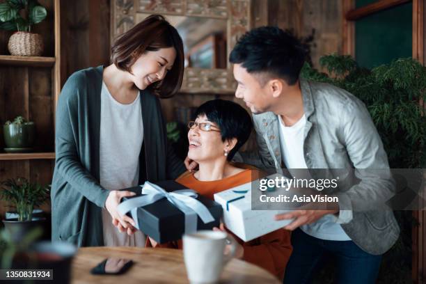 a senior asian mother receiving presents from her daughter and son at home. family love. the joy of giving and receiving - elderly receiving paperwork stock pictures, royalty-free photos & images