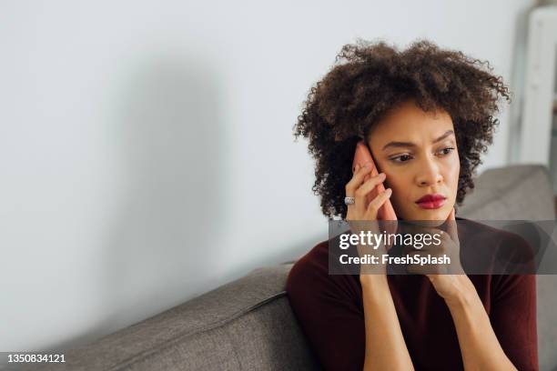 worried business woman talking on a mobile phone at home - anxious stockfoto's en -beelden