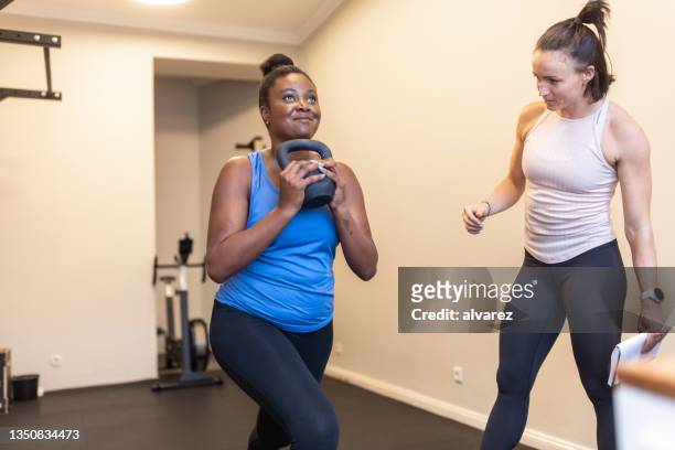 woman exercising in gym with personal trainer - black female bodybuilder stock pictures, royalty-free photos & images