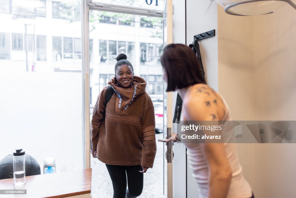 Fitness instructor welcoming a woman at a pilates studio