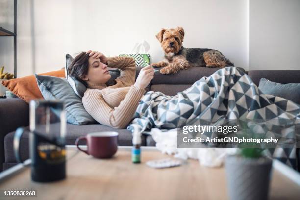 young sick woman lying on sofa at home - immune system stock pictures, royalty-free photos & images