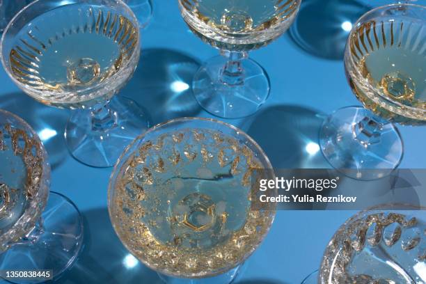 top view of repeated champagne in glasses on the blue background - champagnekleurig stockfoto's en -beelden