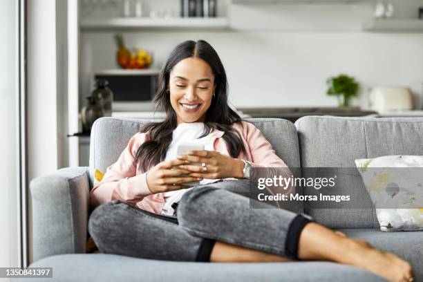 feliz mujer mensajería de texto en un teléfono inteligente en casa - woman texting fotografías e imágenes de stock