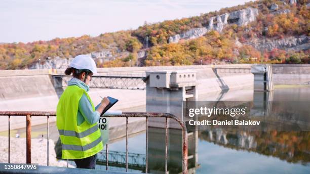 wartungsingenieurin, die im wasserkraftwerk arbeitet. erneuerbare energiesysteme. - wasserkraft stock-fotos und bilder