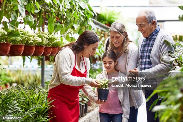 female owner with customers at garden center - tuincentrum stockfoto's en -beelden