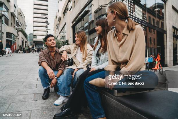 quattro amici stanno parlando insieme in città - ventenne foto e immagini stock
