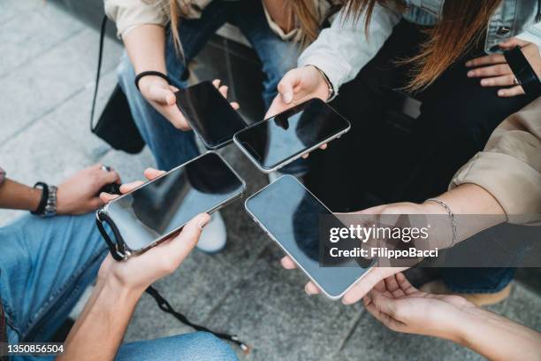 four friends are sharing informations with smart phones - fake news stock pictures, royalty-free photos & images