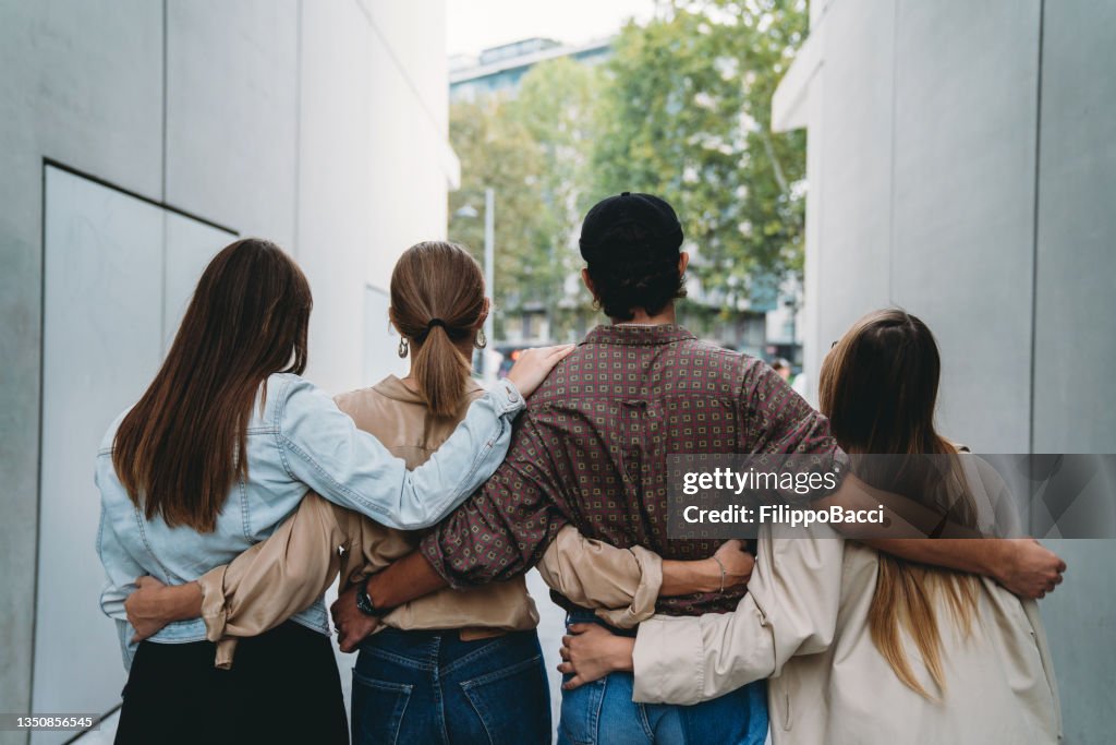 一緒に抱き合う4人の友人の背面図