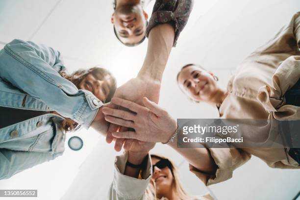 four friends joining hands together - loyalty stock pictures, royalty-free photos & images