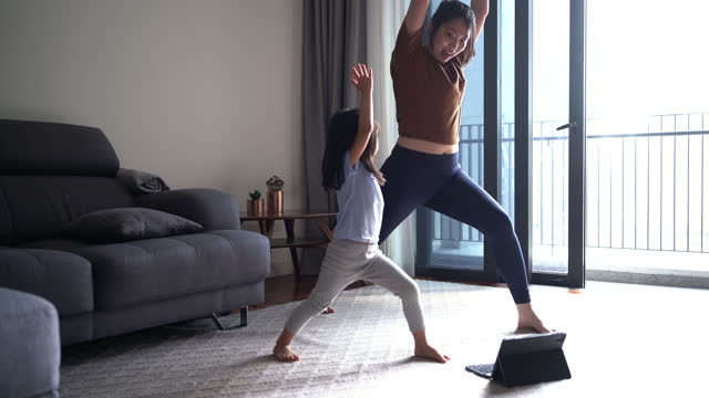 Mother and daughter having online yoga class at home