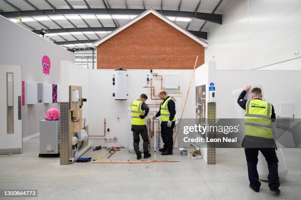 Plumbing engineers install the pipework for a heat pump system at the Octopus Energy training facility on November 02, 2021 in Slough, England. Ahead...