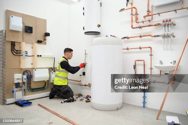 Plumbing engineer installs the pipework and water tank for a heat pump system at the Octopus Energy training facility on November 02, 2021 in Slough,...