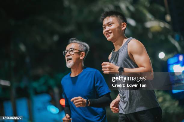 asian chinese active senior man and his son running jogging in the city at night together - malaysia father and son stockfoto's en -beelden