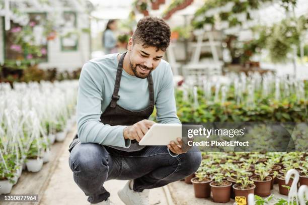 using his tablet to manage the garden center - african farming tools stock pictures, royalty-free photos & images