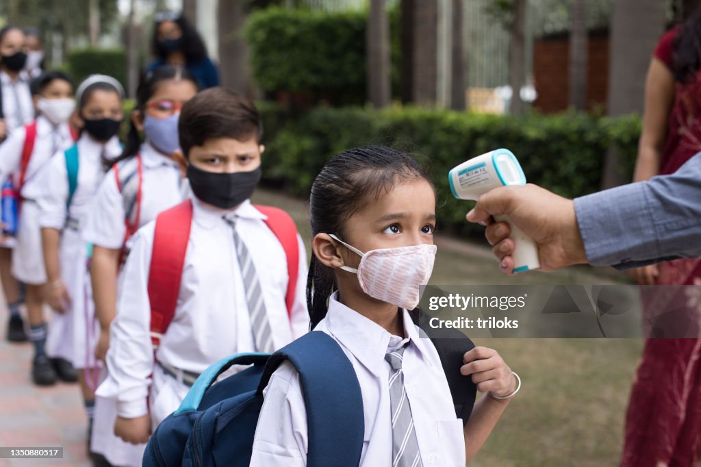 Students getting temperature checked before entering school