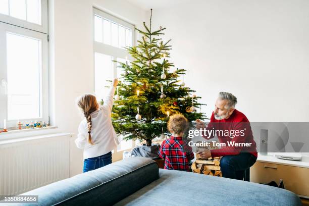 grandpa spending time with grandchildren decorating for christmas - christmas fun photos et images de collection