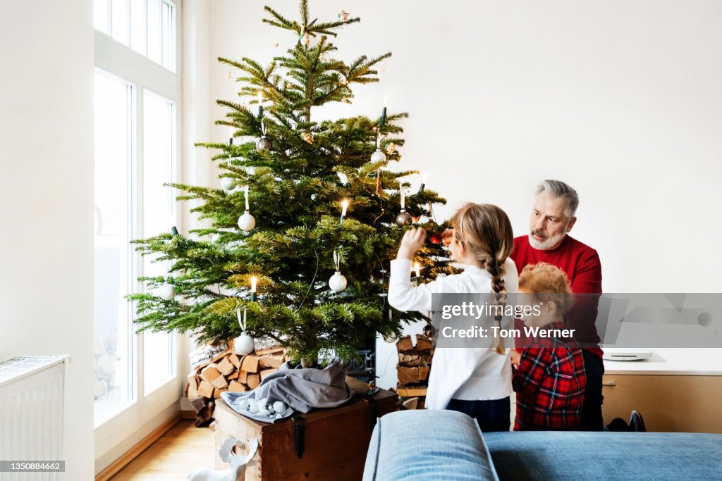 Grandpa Spending Time With Grandchildren Decorating Christmas Tree