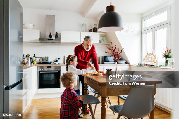 grandpa preparing lunch for young grandchildren - family in kitchen stock-fotos und bilder