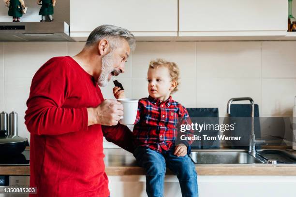 grandpa being playful with grandson while having snack - wear red day - fotografias e filmes do acervo
