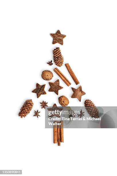 wooden stars, nuts, anise stars, cinnamon sticks and pine cones laid out in the shape of a christmas tree. white background. flat lay. - cinnamon stock pictures, royalty-free photos & images