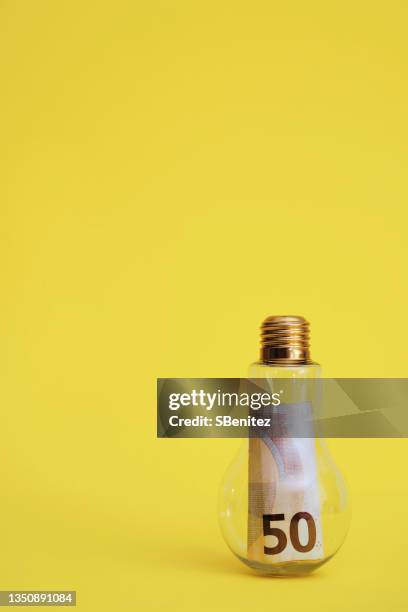 a light bulb with a € 50 bill inside it, representing the rise in the price of electricity - high rise stock-fotos und bilder