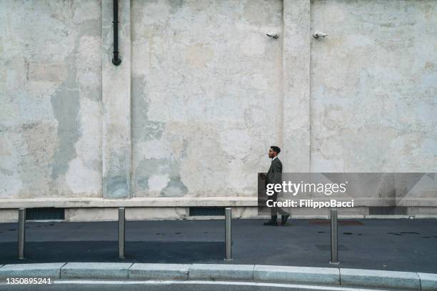 an elegant businessman is walking in the city, commuting to the office - milan business stock pictures, royalty-free photos & images
