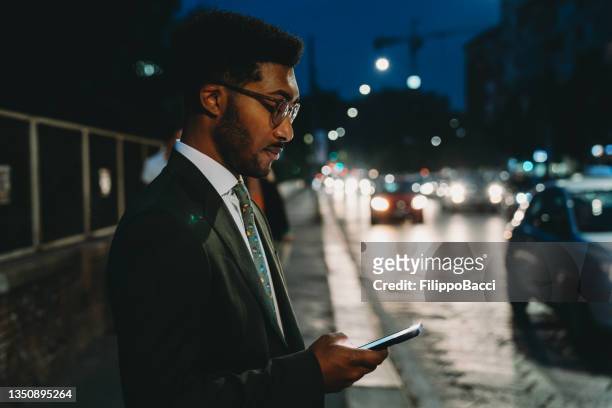 junger erwachsener geschäftsmann benutzt nachts sein handy in der stadt - fachmann auto smartphone stock-fotos und bilder