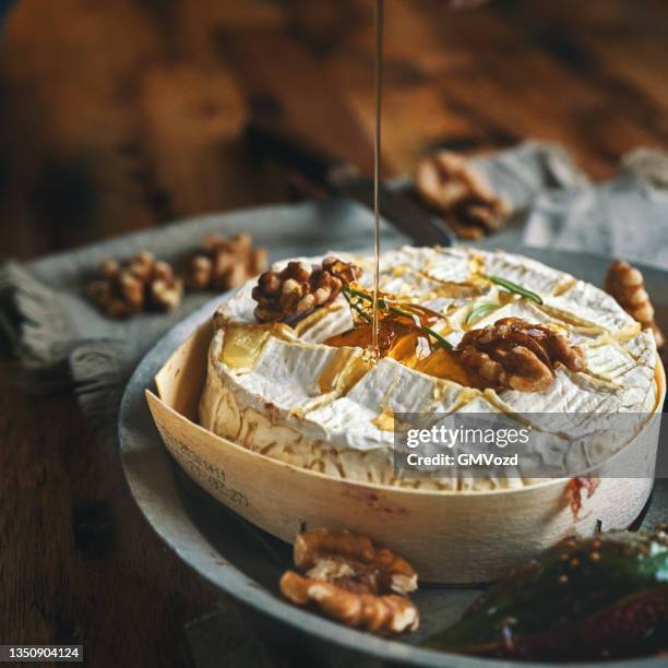 baked camembert cheese served with honey and fresh figs - camambert stockfoto's en -beelden