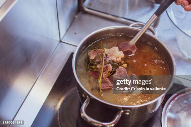 bone broth, cooking leftover bone broth in a large pot - fond stockfoto's en -beelden