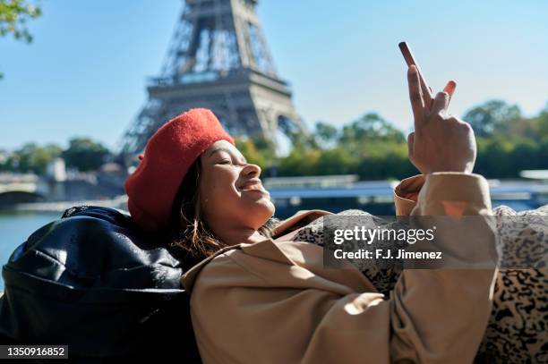 woman lying down using mobile phone near eiffel tower - person eiffel tower stock pictures, royalty-free photos & images