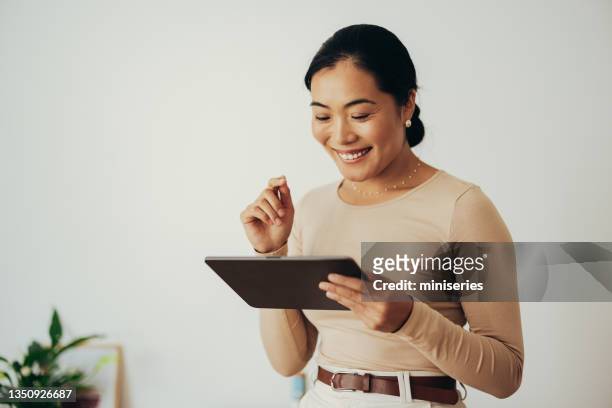 glückliche geschäftsfrau mit digitalem tablet zu hause - asian woman reading stock-fotos und bilder