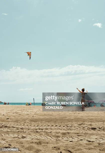 rear view of caucasian teenager girl flying a kite on beach during summer against blue sky - ar 15 imagens e fotografias de stock