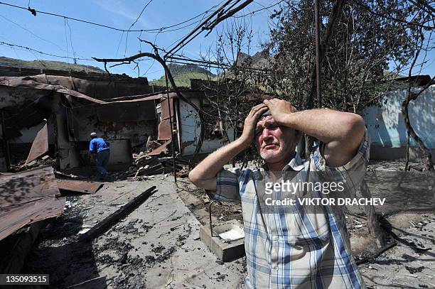 File picture taken on June 14 shows an ethnic Uzbek man holding his head in his hands as he stands beside the wreckage of his home, which was burned...