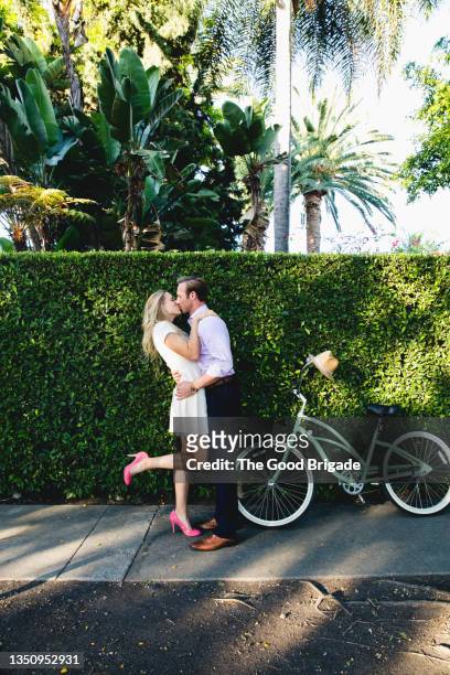 couple kissing on sidewalk next to bicycle on sunny day - dar uma ajuda imagens e fotografias de stock