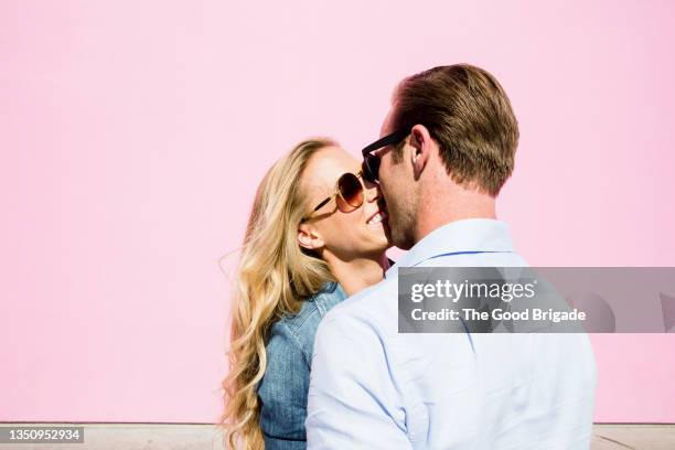 happy couple kissing in front of pink background - snog stock pictures, royalty-free photos & images