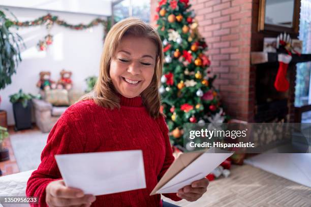 beautiful mature woman looking at all the christmas cards she has received while smiling very happy - greeting card and envelope stock pictures, royalty-free photos & images