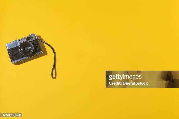 35mm analog photo camera on the left, with copy space, on a yellow background. vintage, retro and analog photography concept. - camera imagens e fotografias de stock