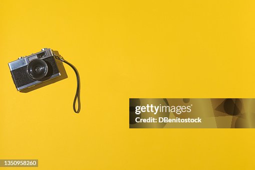 35mm analog photo camera on the left, with copy space, on a yellow background. Vintage, retro and analog photography concept. 35mm analog photo camera on the left, with copy space, on a yellow background. Vintage, retro and analog photography concept.