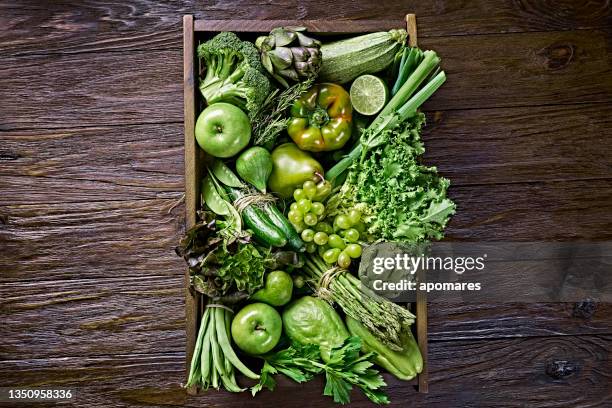 table top view background of a variation green vegetables for detox and alkaline diet. set in a crate on a wooden rustic table with a frame - alkaline stockfoto's en -beelden