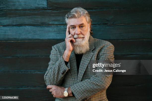 old man, with a suit jacket, with a thoughtful and worried expression. with a street wall in the background. old men, beard, bearded, hipster, barber, time, dreams, finance and retirement concept. - hipster senior man stock pictures, royalty-free photos & images