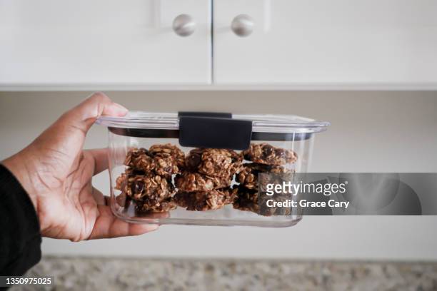 woman stores homemade banana oatmeal chocolate chip cookies in container - sotto vuoto foto e immagini stock