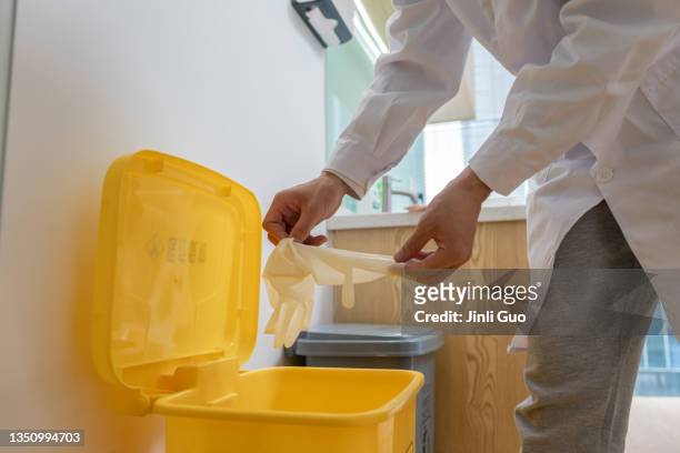 the dentist throws the disposable latex gloves into the corresponding trash can after the operation - rubber gloves stockfoto's en -beelden