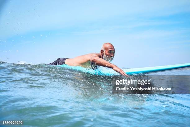 senior man paddling waves of sea in neighborhood - asian exercise stock pictures, royalty-free photos & images