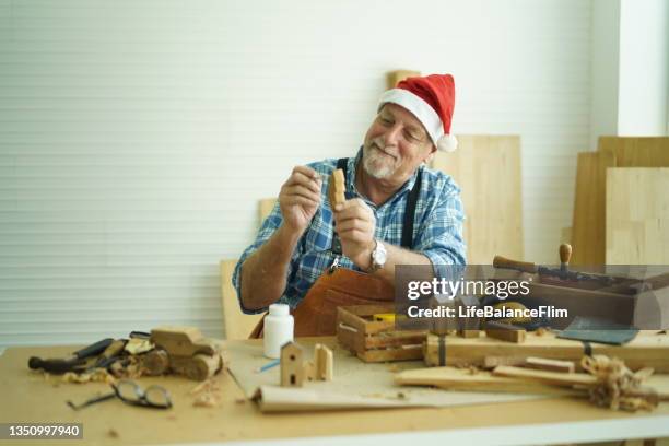 senior carpenter wearing santa hat. - craft santa claus stock pictures, royalty-free photos & images