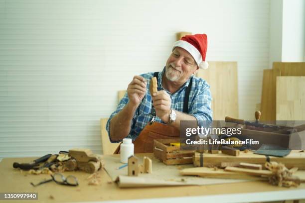 senior carpenter wearing santa hat. - santas workshop stock pictures, royalty-free photos & images