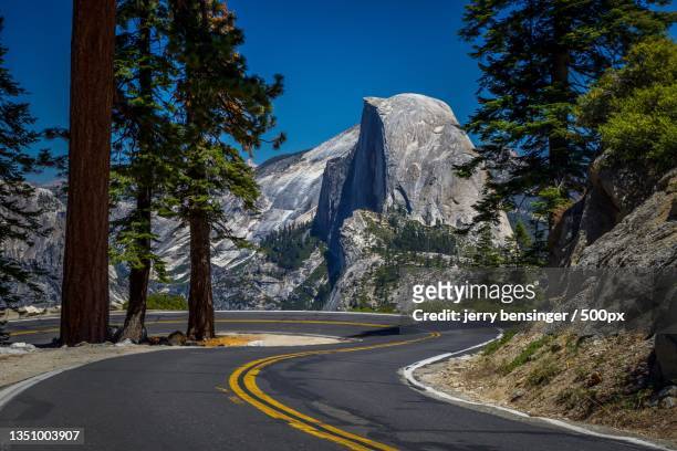 empty road by trees against sky,yosemite valley,california,united states,usa - half dome stock-fotos und bilder