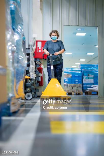 blue collar worker using an empty pallet jack - pallet jack stock pictures, royalty-free photos & images