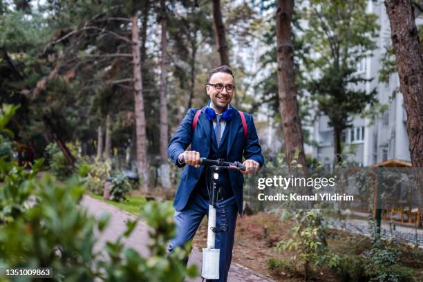 young  businessman riding electric scooter on the way of work - smart city life stock pictures, royalty-free photos & images